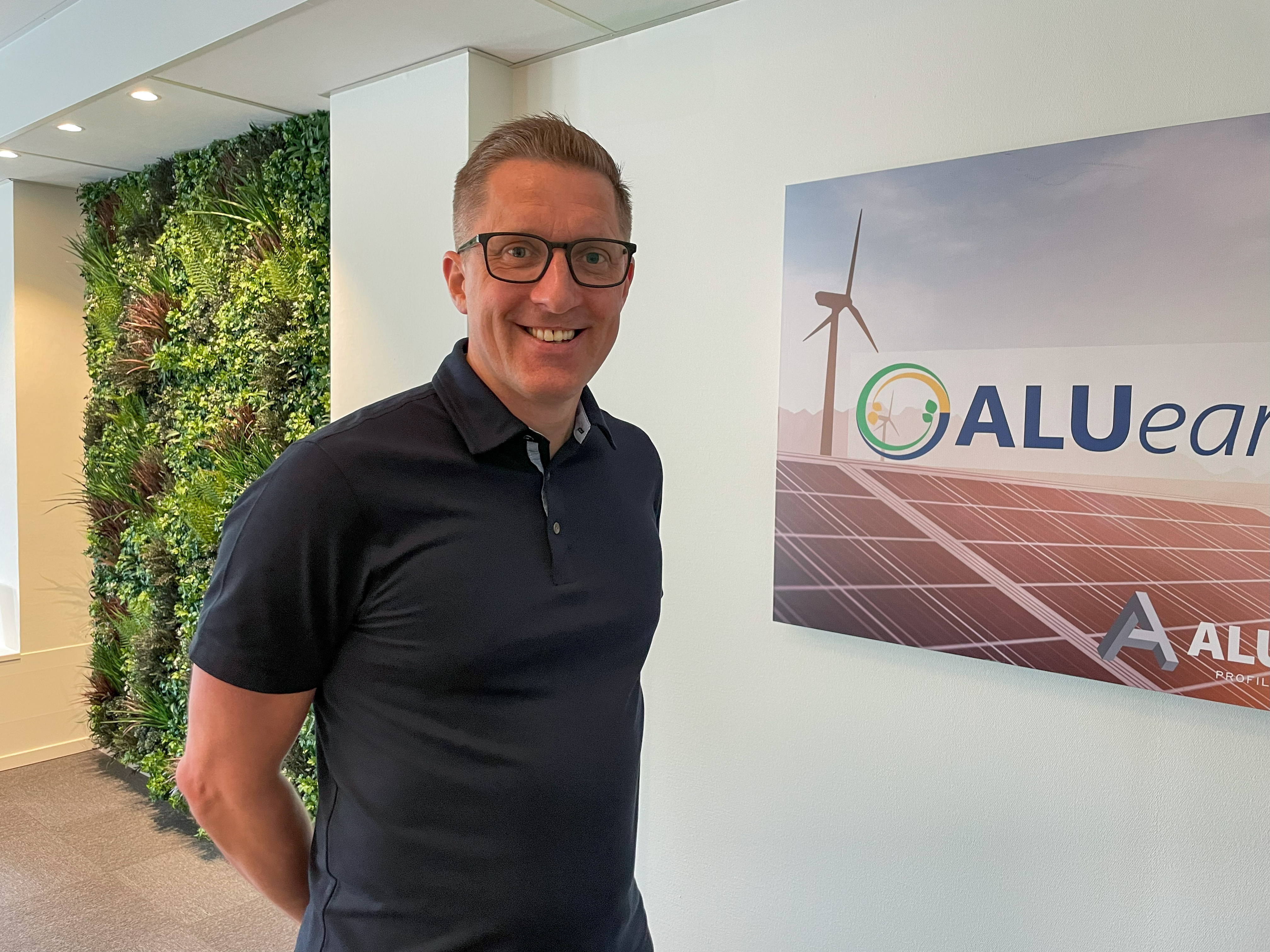 Distrikts&auml;ljaren Daniel Herbertsson ber&auml;ttar om ALUearth framf&ouml;r skylt med logotype.